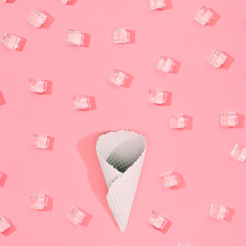 Cone with straw with ice cubes pattern on pastel pink background