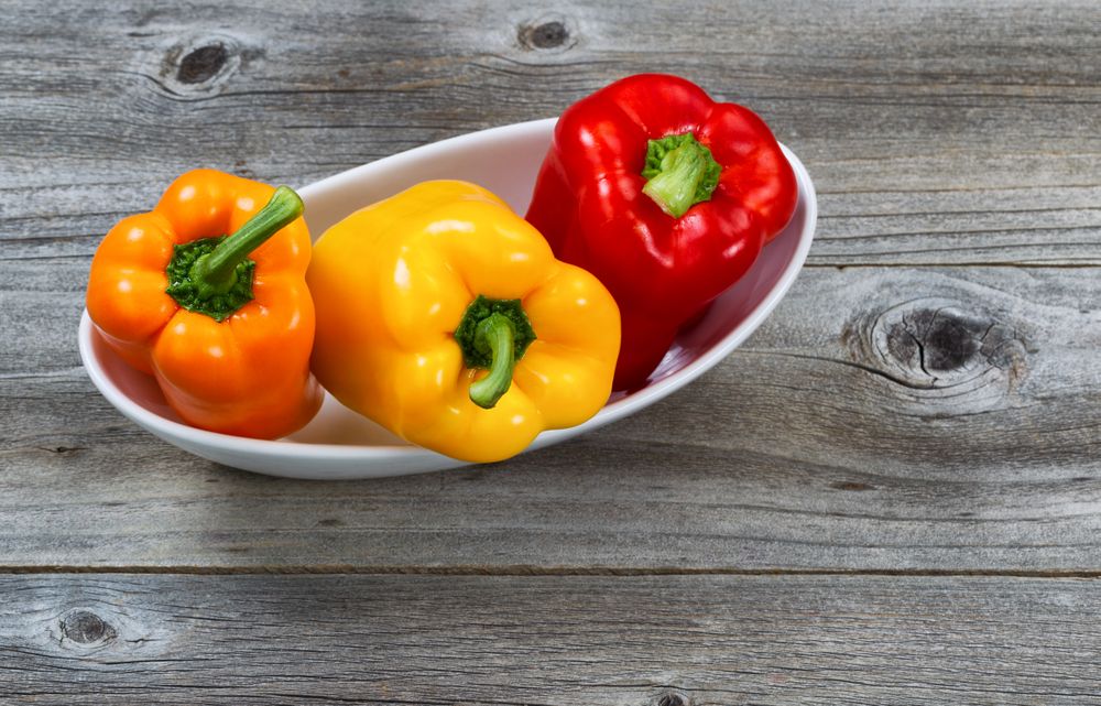 Fresh Bell Peppers in bowl on rustic wood