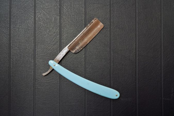 Rusty metal razor on black background