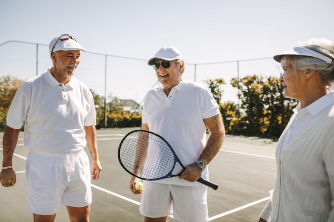 Older people playing tennis on a sunny day