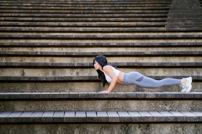 a young female fitness athlete doing push-ups on a wooden steps