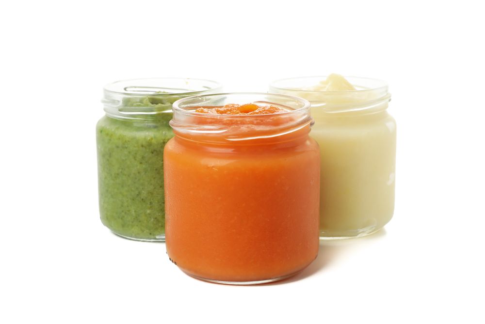 Glass jars with healthy baby food isolated on plain background