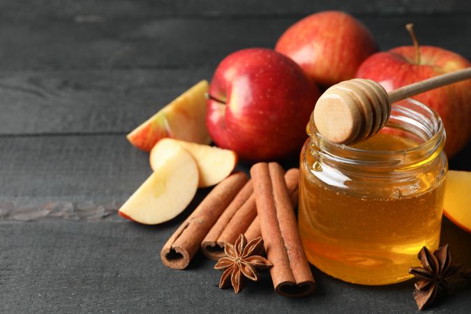 Top view of apples cinnamon sticks and honey pot