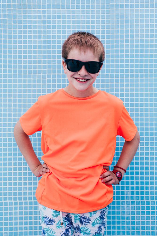 Happy boy in sunglasses against tiled wall
