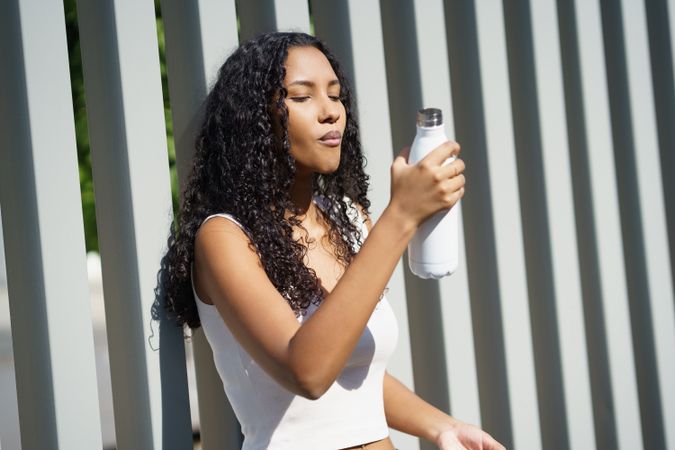 A Young Woman Happily Enjoying Refreshing Hydration While Being Outdoors in Nature