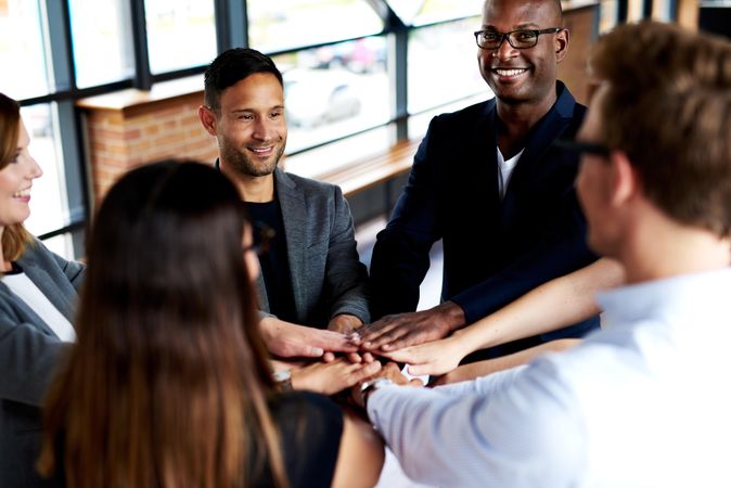 Group of business colleagues smiling and holding their hands together