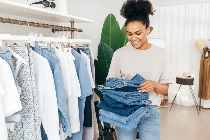 Woman with a stack of jeans in a bright boutique