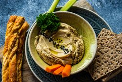 Top view of traditional hummus spread with breadsticks and crackers to dip