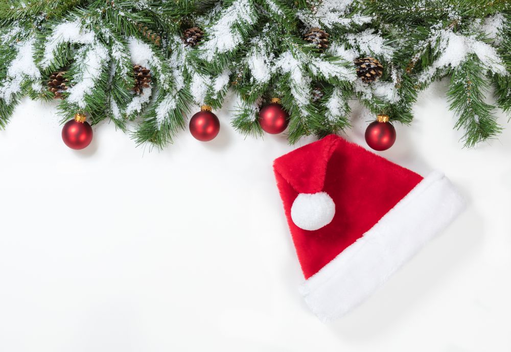 Snowy Christmas branches with Santa Claus hat and red ornaments