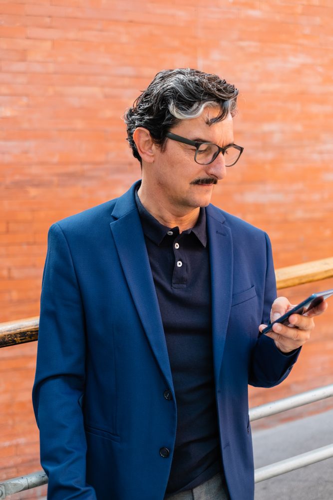 Mature businessman in blue jacket using smartphone
