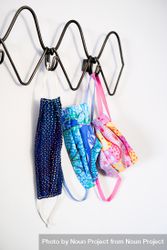 Blue and pink patterned PPE masks hanging on coat rack by door bxAya0