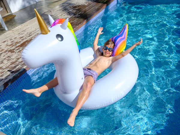 Content kid lying on inflatable ring and floating in swimming po