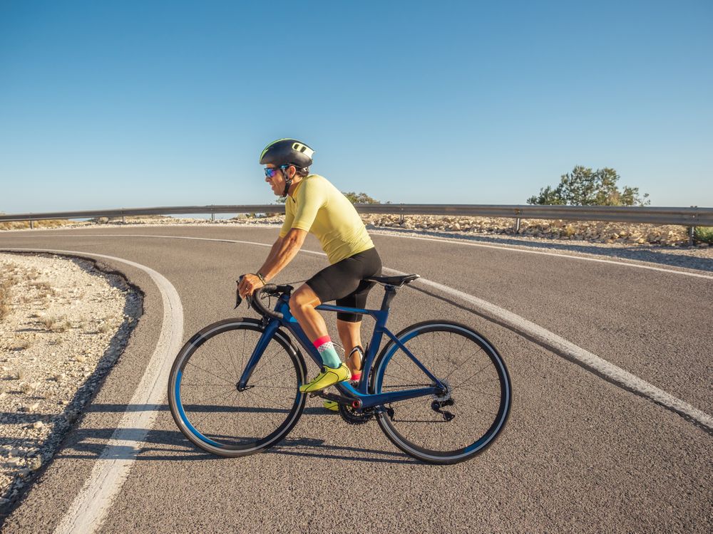 healthy man riding a bicycle on a mountain road in a sunny day