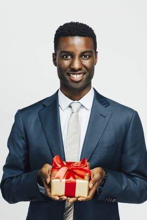 Happy Black man presenting present wrapped in gold paper