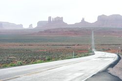 Asphalt road at scenic mountain valley and power line