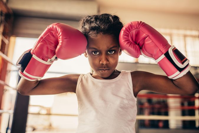Close up of a girl wearing boxing gloves standing inside a boxing ring