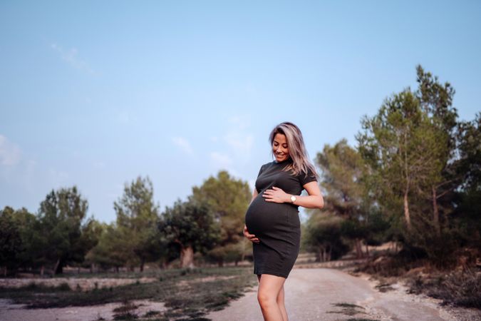 Charming pregnant woman standing on walkway in park