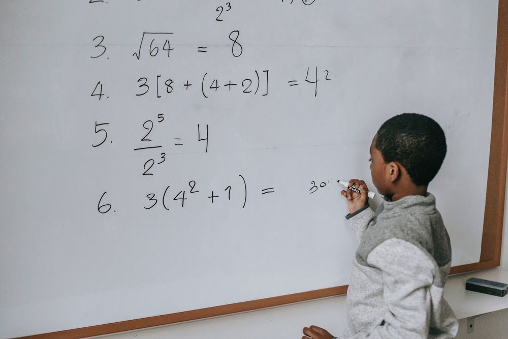 Back view of student solving math exercises on light board