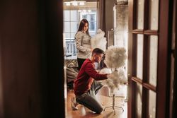 Young couple expecting baby arranging Christmas tree at home