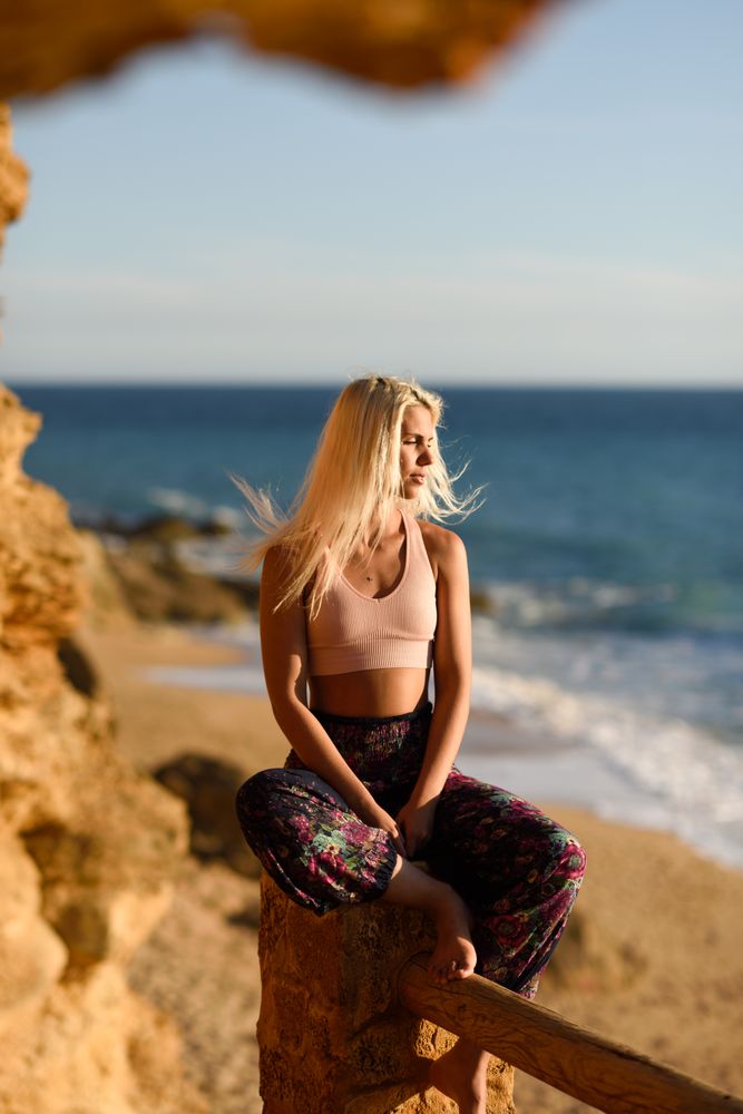 Blonde woman relaxing on fence over looking beach