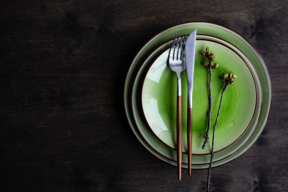 Green plate table setting with cherry blossom, with copy space