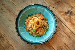 Bowl of delicious fried rice with shrimps on wooden table