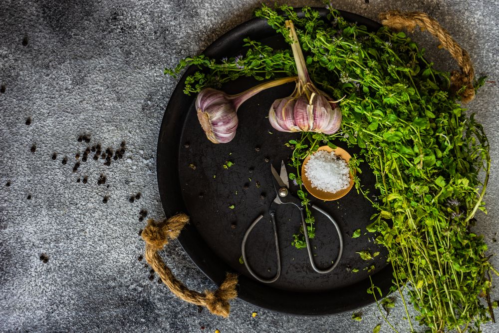 Top view of cooking concept with marjoram and garlic on plate