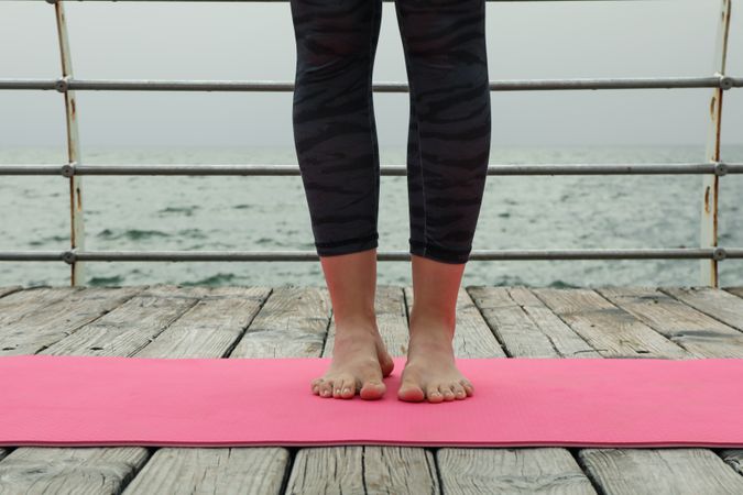 Female legs on yoga mat on wooden floor at sea