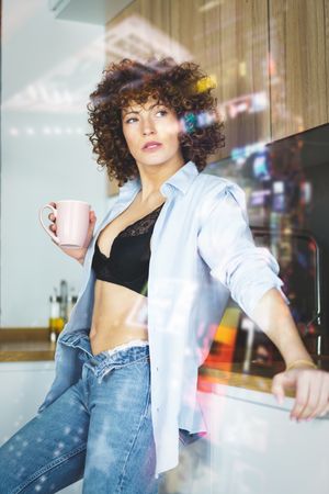 Woman lounging in her kitchen with coffee seen through glass