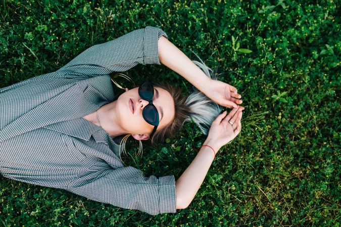 Woman in stylish suit lying in grass
