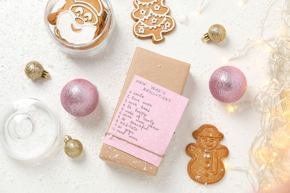 Cookies and paper with list on box on plain background, top view