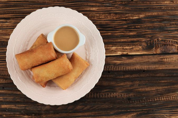 Top view of Chinese egg rolls served on plate on wooden table