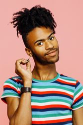 Smiling young man with earrings, happy sign on his striped shirt and hand up