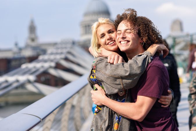 Male and female smiling and hugging on bridge in London