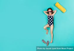 Top view of girl wearing swimwear and sunglasses lying on blue background 5Xpwo5