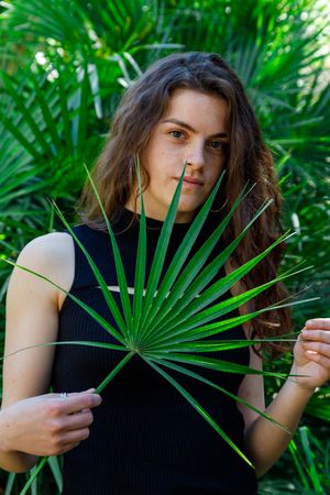 young female among green palm leaves