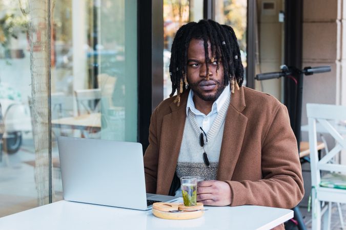 Serious Black man with espresso and glass of water in cafe