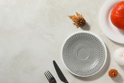 Cutlery, plates and candles on light background, space for text
