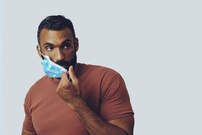 Male adjusting his medical face mask looking at camera in studio shoot