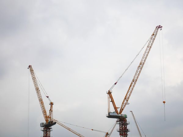 Two cranes under cloudy sky