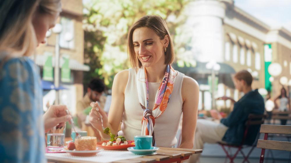 Portrait of a Joyful Female Spending Time with a Friend on a Cafeteria Terrace, Enjoying a Healthy Vegetarian Salad.