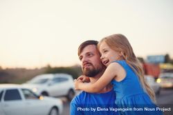 Female child being held by her father standing with cars in background 0g2lWb