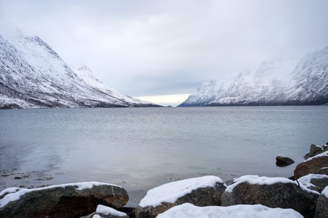 Scenic view from sea stones on snowy mountains