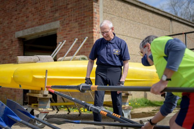 Two older men preparing oars before rowing