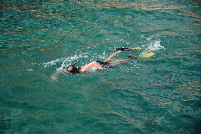 Boy wearing flippers and swimming in sea water