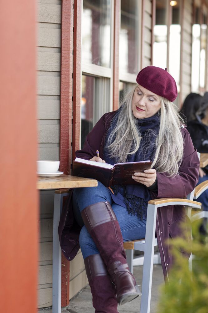 Woman in a beret writing down her ideas into a notebook