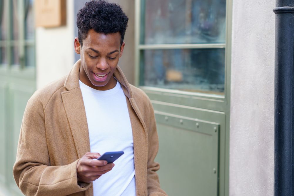 Cuban male looking down at his phone while walking down the street
