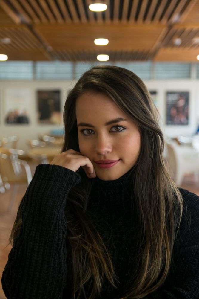 Woman sitting along bookshelves and looking at camera