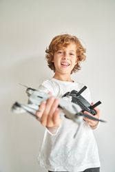 Cheerful preteen boy showing drone copter with remote control