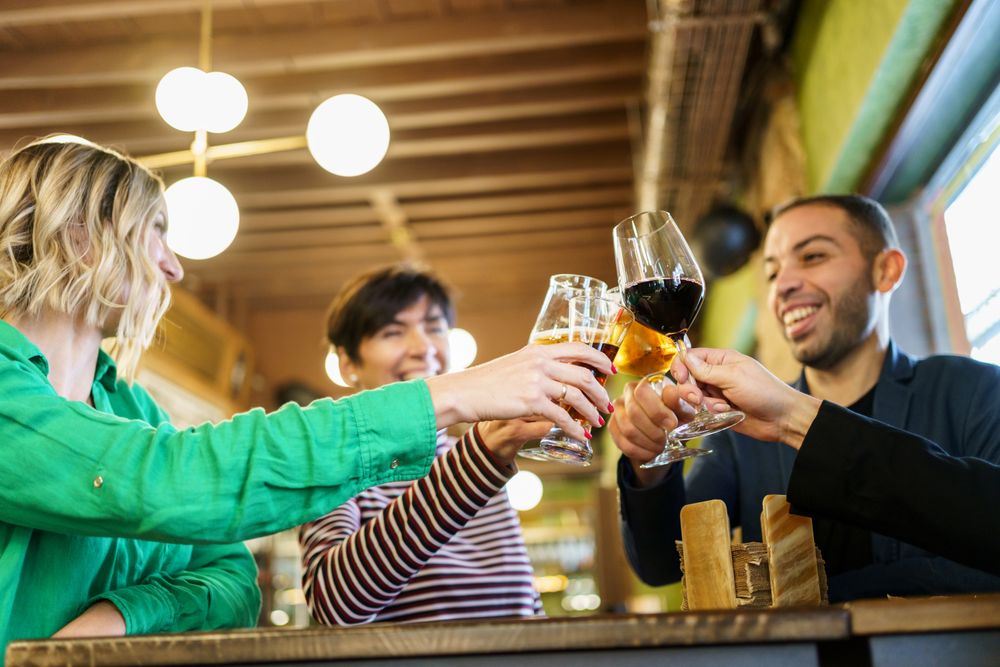 Group of friends clinking beer and wine in bar